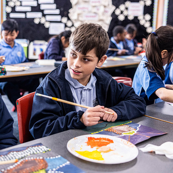 Student painting in the classroom at St John Vianney's Primary School Doonside